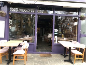 Purple framed door ahead. Push to open. Seating on both sides, outside door.