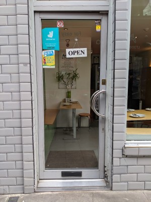 Glass door with grey frame and metal hand on right. Push to open.