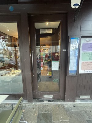 Glass push door with small step as part of the door frame. Push from the left to open. Handle is situated at centre height on the left.