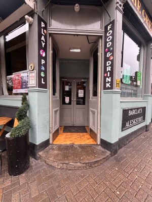 Glass doors with grey wooden frame ahead. Push at center of door to open. Second preceding door after first door.