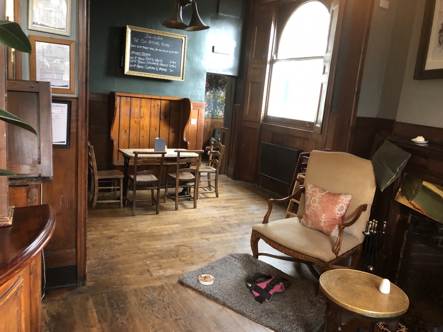 Photo of back right of main area. Table with bench and chairs at back wall. To the right is a low table with two armchairs.
