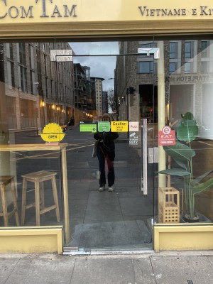 View of the front entrance from the street to the venue. The door is located to the centre right of the shop front. The door pushes open from the right. There is a small bump at the foot of the door.