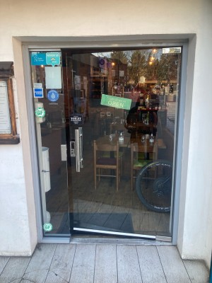 Glass doors with silver handle on left. Push from left to open.