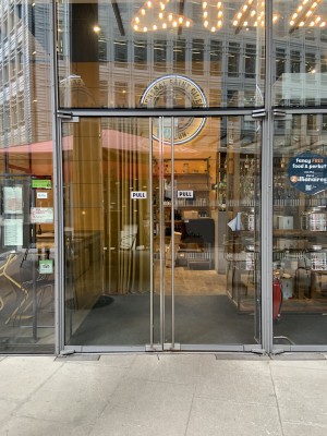 The entrance is to the left of the venue. Door pull to open by ling vertical metal handle where the doors meet.