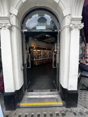 Double glass doors in white stone archway. Push silver metal handles from centre to open.