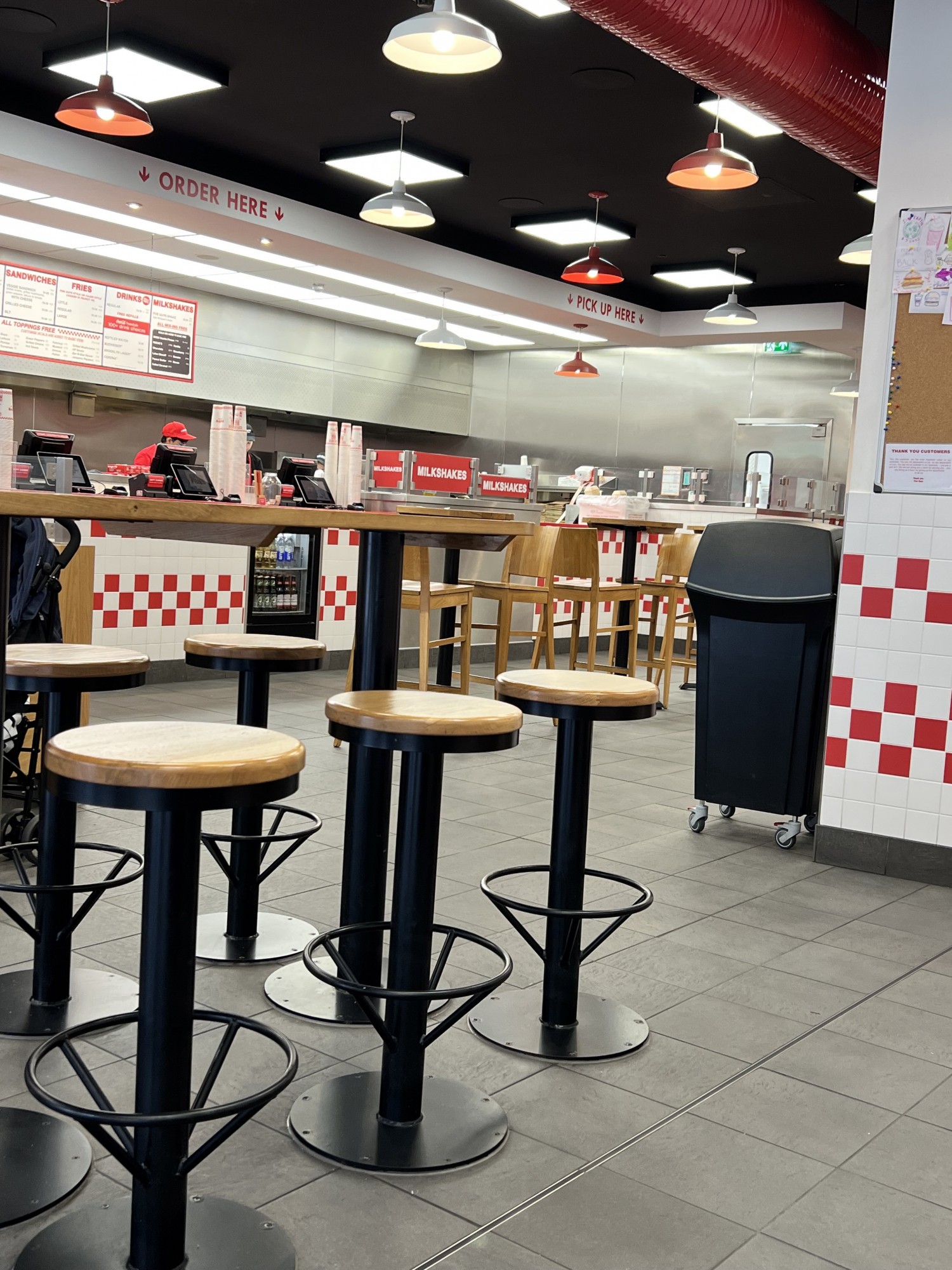 The inside of Chelmsford Five Guys showing the order, collection and some of the bar and bar stool seating.
