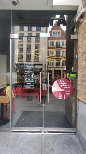 Glass doors ahead. Push in centre via vertical metal handles to open.