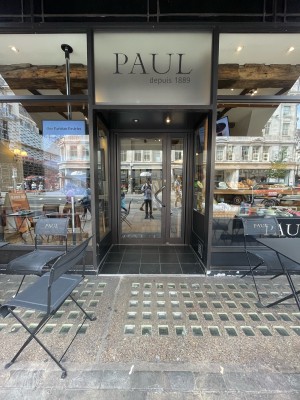 Facing entrance. Path ahead. Ramp at end of path. Metal-framed glass door after ramp. Glass walls either side. Pull silver handle on right to open.