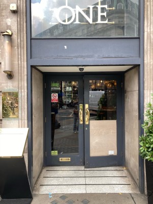 Access via double glass door with grey frame. Pull open via metal handles in center.