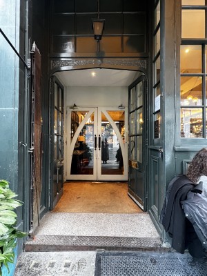 Green wooden and glass panneled doors ahead. Push from centre to open. Step up before door.