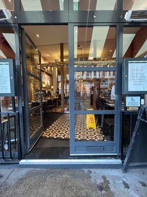Glass doors ahead with dark grey metal frame. Push from centre to open.