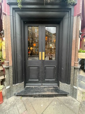 Double black doors with glass panels. Push in center to open.