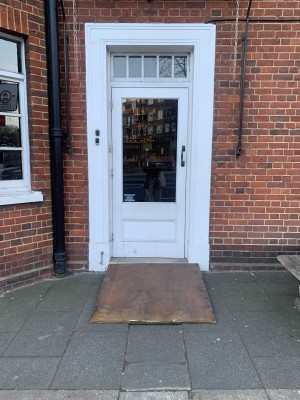 Door on the left side of the venue, with 1 standard sized step in front, with ramp. Pull door from the right to open.
