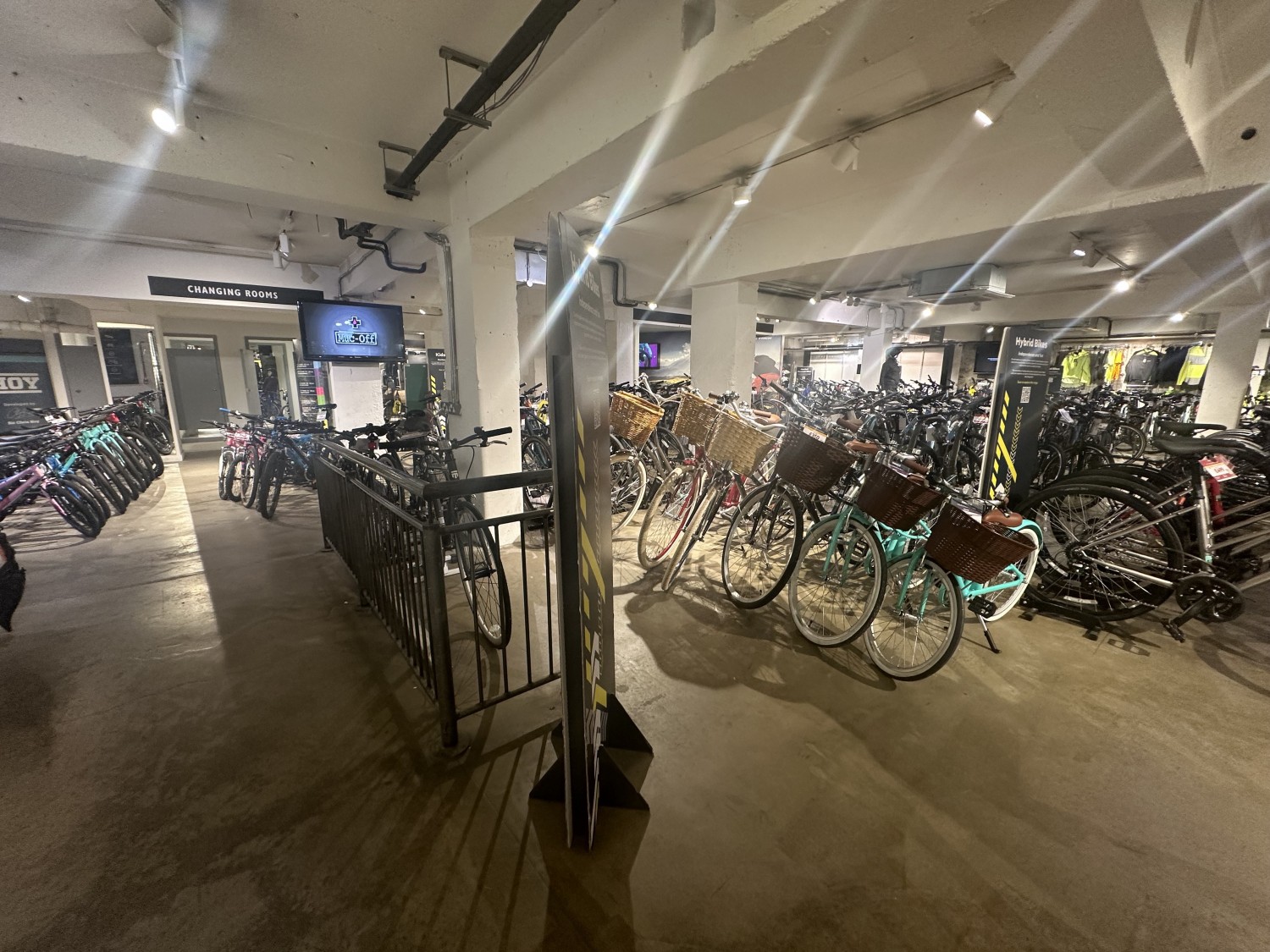 View of the downstairs area. The handrail turns right to another ramp to enter a space with more bikes on display and straight ahead the pathway continues to another area with more bikes on display on the right and left side.
