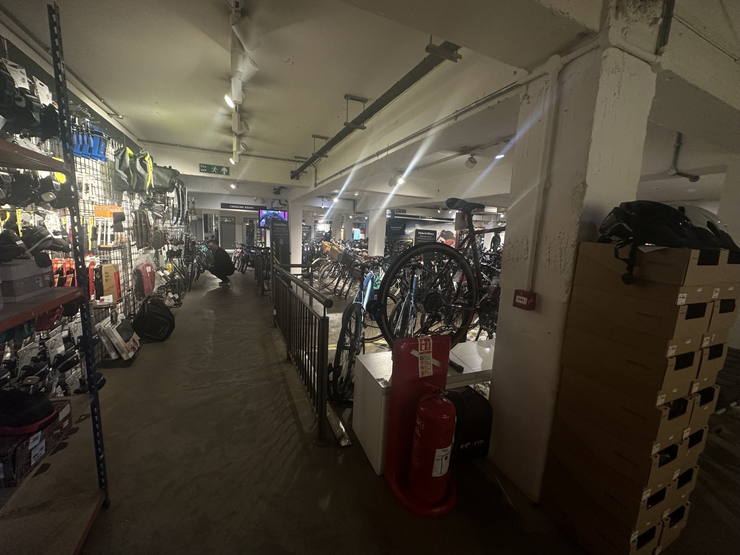 View of the downstairs area. Continuing to the pathway with the shelve of equipment , turning left , there are shelves against the left wall and on the right there is a handrail. Straight ahead there is a ramp.