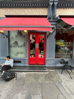 Red wood-framed glass doors ahead. Grey walls on left and right. Two steps before door. No handles. Push at centre to open.