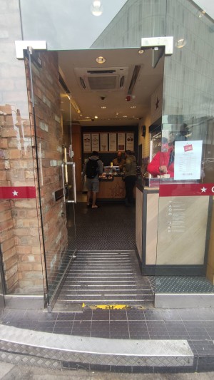 Glass door with metal vertical handle on right. Push to open.