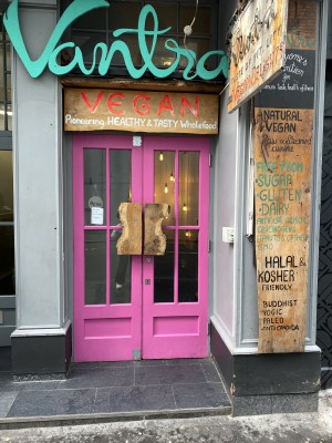 Directly facing the Vantra Vegan door entrance from the street. Double door entrance (two door handles located in middle of the doors) with one step in front of the door.