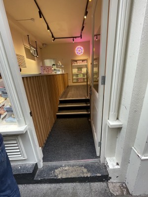 Glass door, with white wooden doorframe. Push on left to open.
