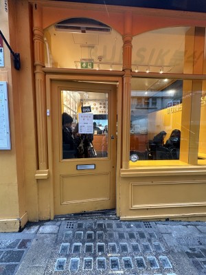 Glass door, with wooden yellow doorframe. Push on right to open.