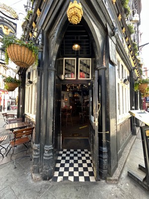 Black domed open archway precedes single black wooden door with glass panel. Pull handle on left to open.