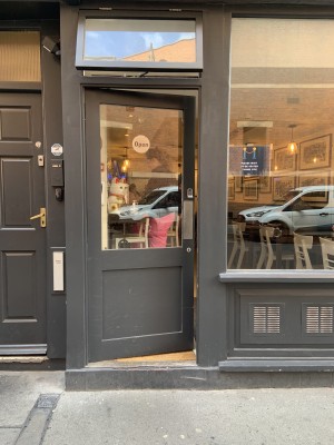 Door to the left of venue pushes to open via without handle on the right of door.