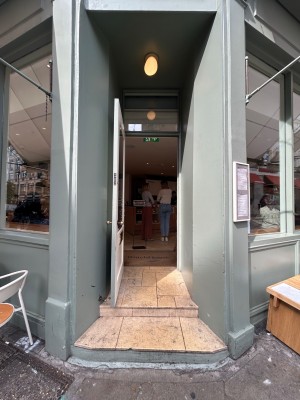 Open archway precedes single white wooden door with large glass panel. Pull gold doorknob on right to open.