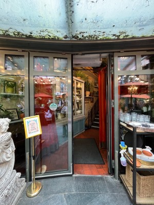 Double glass doors in grey metal frame. Push silver metal panels from centre to open.