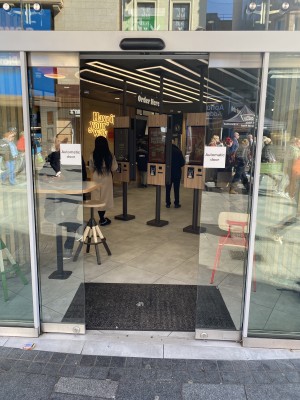Directly facing the main entrance into the Burger King from foot path. Automatic doors in process of filling opening.