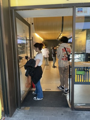 Glass door, with brown doorframe. Gold handle on right. Push to open.