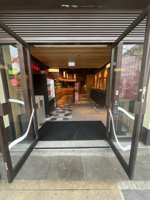 Glass double door, with brown doorframe. Handles at centre. Pull to open.