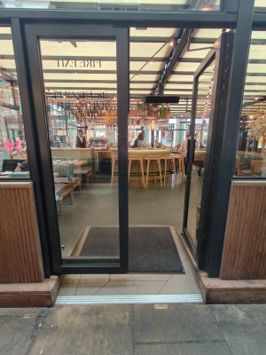 From left of venue facing black framed door. Push black metal handles in centre of door to open.