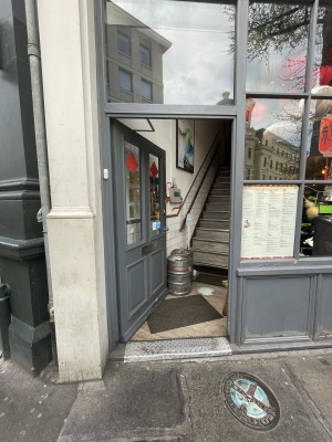 View of the main entrance to the venue, located to the left of the venue front. There is a door that pushes open from the right. There is a step at the foot of the door.