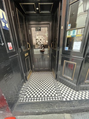 Double black wooden doors with windows. Push metal handles from centre to open. Single black wooden door with window behind. Push from right to open.