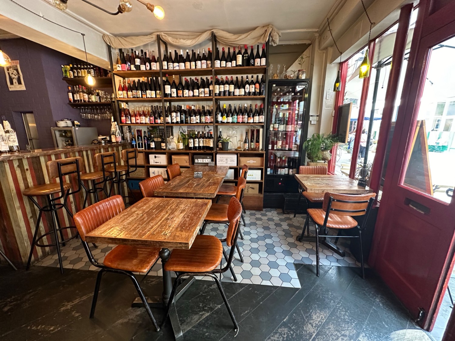 From entrance looking right at tables and chairs along left and right. Bar with high stools to far left.