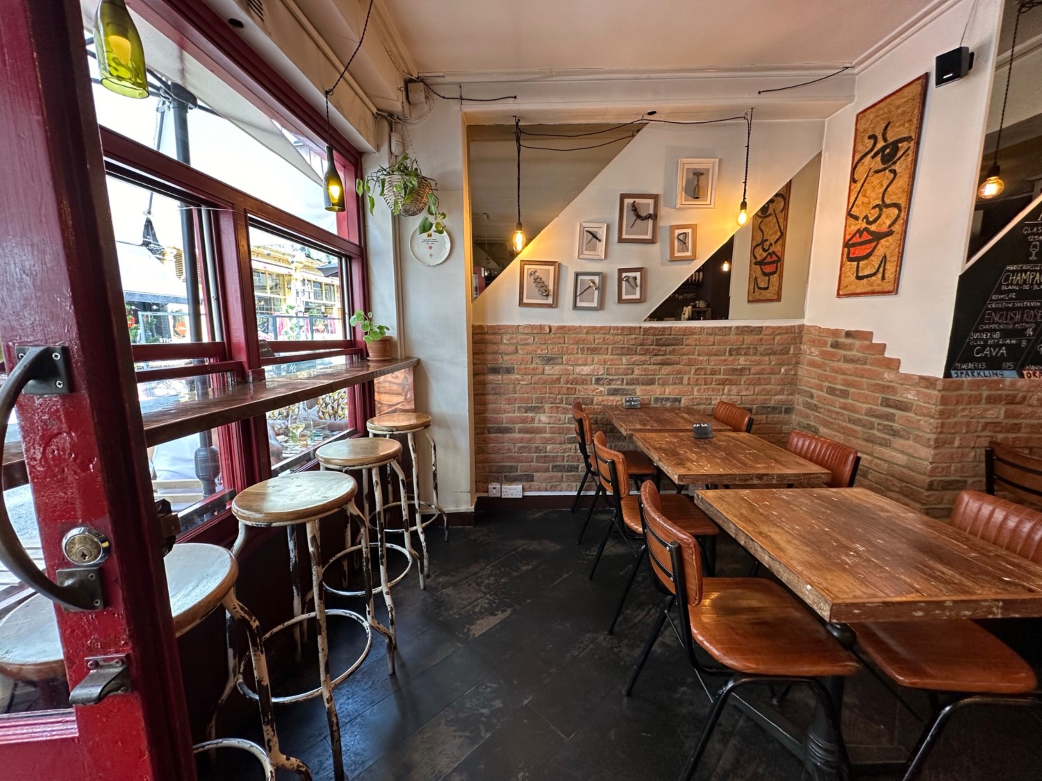 From entrance looking left at path ahead. High table with stools along left. Tables and chairs along right.