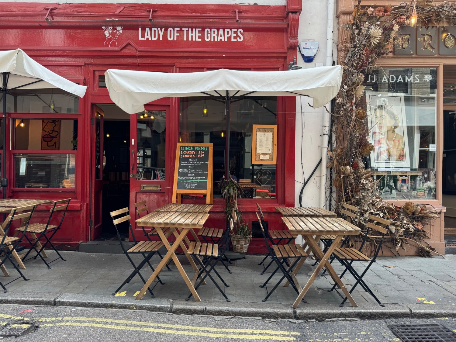 Outdoor seating area on street with seated height tables and chairs and adjustable shelter. One step to access seating area from street