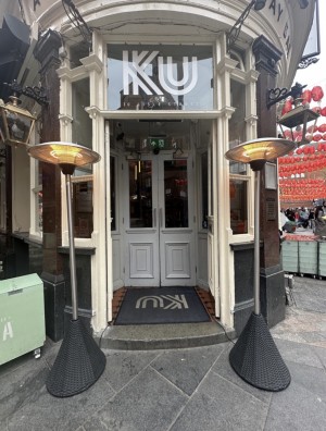 Double cream wooden doors with large glass panels. Push from middle to open. Lamps to left and right of door.