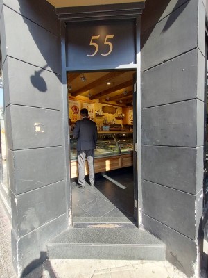 Glass door with black frame, push from left to open.