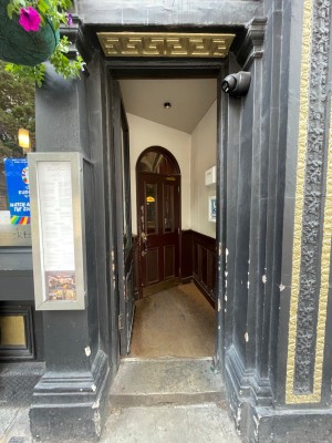 Wooden door with glass panel, handle at right. Push to open.