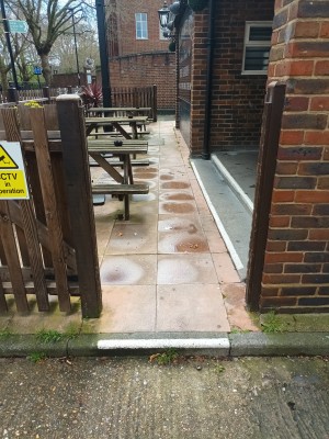 From right sidewalk facing venue. One small step up to wooden fence door. Push to right to open. Path in centre to main door on right.