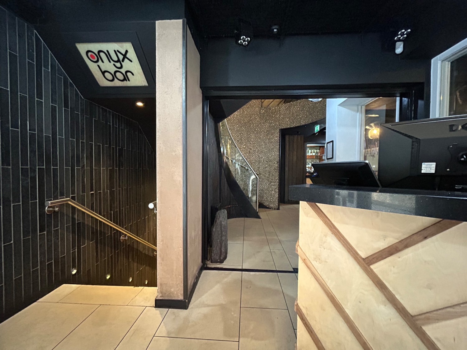 From doorway, facing straight. Path to stairs on left. Host stand on right. Path in middle leads to archway into main area.