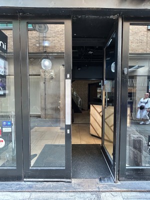 Double glass doors with black frame. Push silver pads in middle to open.