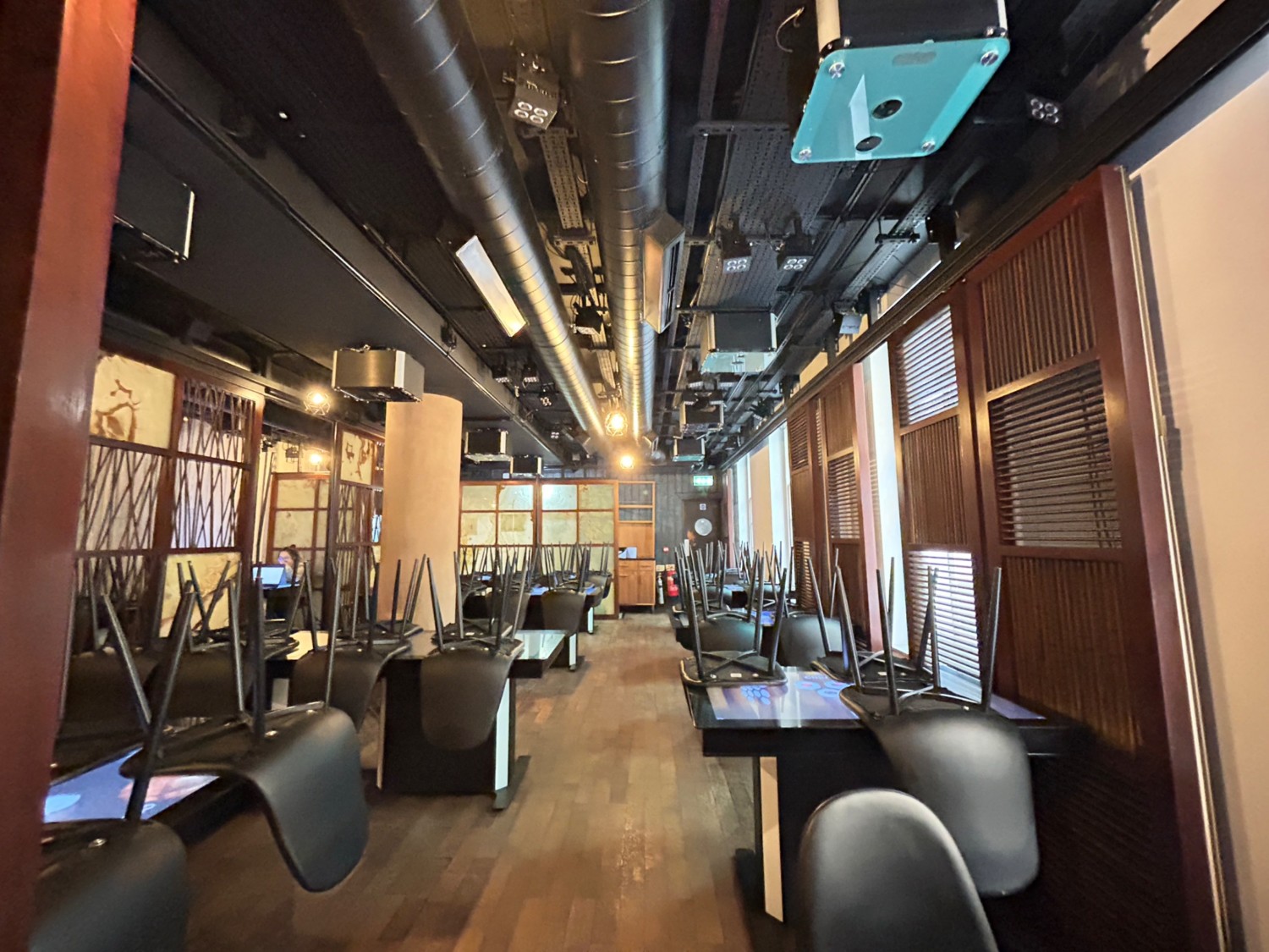 From right of stairs, facing straight. Tables and chairs along left and right. Path in middle.