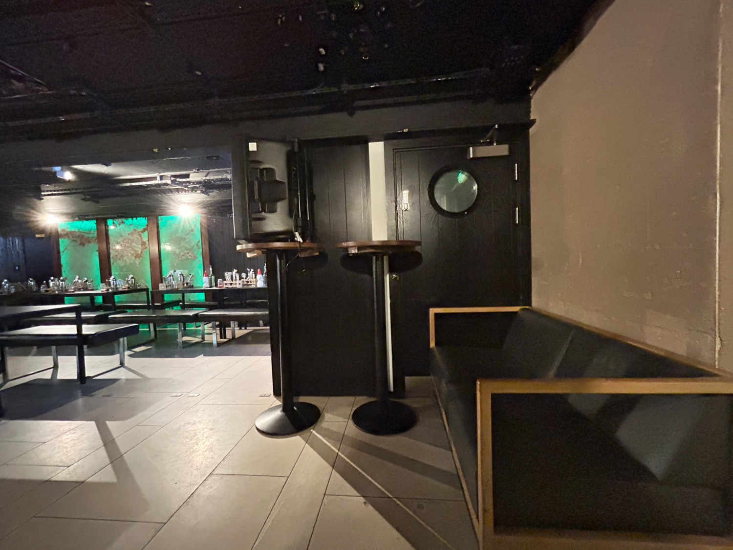 From doorway, facing right. Bench along right. High tables ahead along back wall. Tables and benches on left.
