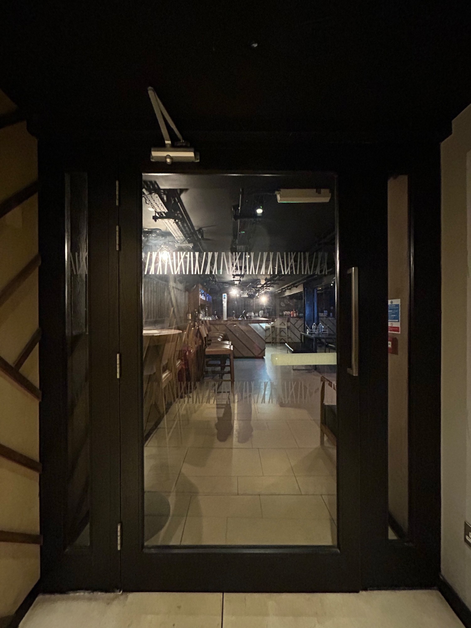 From end of path, facing straight. Single glass door with black frame ahead. Pull vertical silver handle on right to open.
