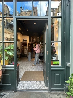 Single dark green wooden door with gold pad on right and glass panels. Push to open.