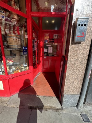 Ramp straight ahead and on the left main door entrance. Wood and glass door. Push door, handle on the right.