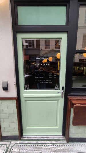 Glass door with mint frames ahead. Push to right via metal handle.