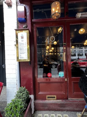 Main entrance, glass door with red wood frame. Handle on the right side, middle of door. Large step.